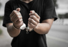 Close-up of hands in handcuffs against an outdoor background