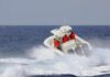 A speedboat with passengers navigating through rough ocean waves