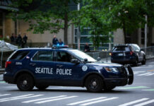 Seattle police SUV parked on a city street with blue lights flashing
