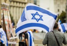 Defamation Battle: Netanyahu Slams NY Times Person holding an Israeli flag at a public demonstration
