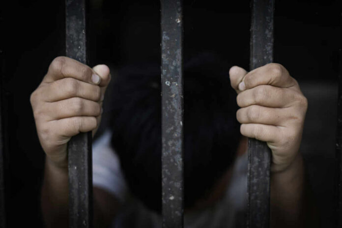 A childs hands gripping prison bars, conveying a sense of confinement and distress