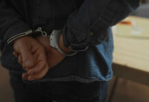 Hands behind back in handcuffs, indicating an arrest