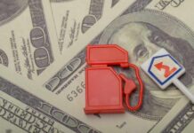 Red fuel pump toy next to hundred dollar bills