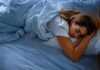 A woman sleeping peacefully on a bed with blue sheets