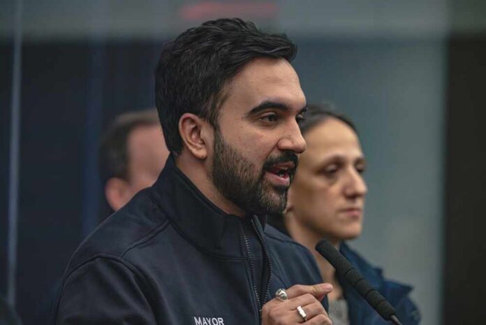 A man in a mayor's jacket speaking at a press conference with a woman in the background