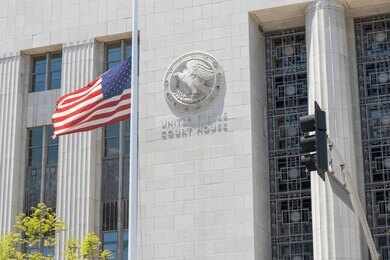 United States courthouse facade with American flag at half-mast