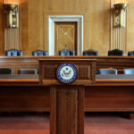War Powers Showdown: Trump Holds Cards Wooden podium with the United States Senate seal in an empty Senate chamber
