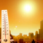 A thermometer held against a sunset city skyline