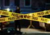 Base Love Triangle Turns Deadly Police tape marking a crime scene with blurred figures in the background