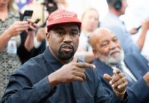 A man wearing a red cap gestures during a discussion at a political event