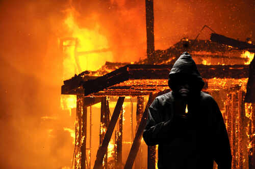 Arsonist A hooded figure holding a lighter in front of a burning structure