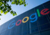 Google logo displayed on a glass building with green leaves in the foreground