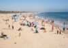 Crowded beach with people sunbathing and playing in the water