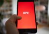 Hand holding smartphone with red app screen