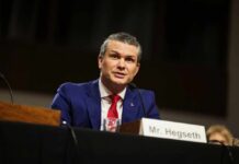 Man in a blue suit speaking at a government hearing
