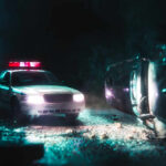 A police car with flashing lights at the scene of a flipped vehicle accident
