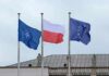 Mystery Factory Hides Inside Poland’s Tank Deal Three flags on poles including NATO, Poland, and the European Union