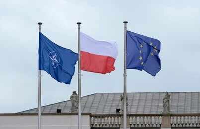 Three flags on poles including NATO, Poland, and the European Union