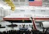 Presidential aircraft in a hangar with a podium and crowd below