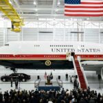 Presidential aircraft in a hangar with a podium and crowd below