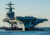 Carrier Repaired, Retirement Looms—Why? Aircraft carrier guided by tugboats in a harbor