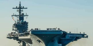 Aircraft carrier guided by tugboats in a harbor