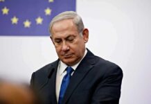 ICC Twist: NYC Mayor Targets Netanyahu man in suit at podium with EU flag in background