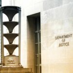 Department of Justice building exterior with sign and metal sculpture