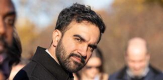 Man in a dark coat outdoors looking toward the camera