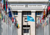 Rule Change Quietly Rescues Syria’s Vote United Nations building with multiple international flags in front