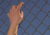 Hand gripping a chain-link fence