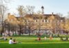 Students relaxing on a campus quad in front of a brick academic building