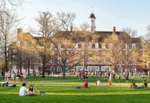 Students relaxing on a campus quad in front of a brick academic building
