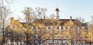 Students relaxing on a campus quad in front of a brick academic building