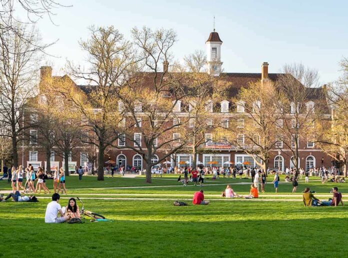 shutterstock_1037739901 Students relaxing on a campus quad in front of a brick academic building