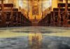Church interior with wooden pews facing ornate altar