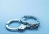 Metal handcuffs on a light blue surface