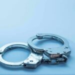 Metal handcuffs on a light blue surface