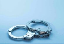 Metal handcuffs on a light blue surface