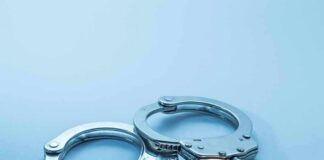 Metal handcuffs on a light blue surface