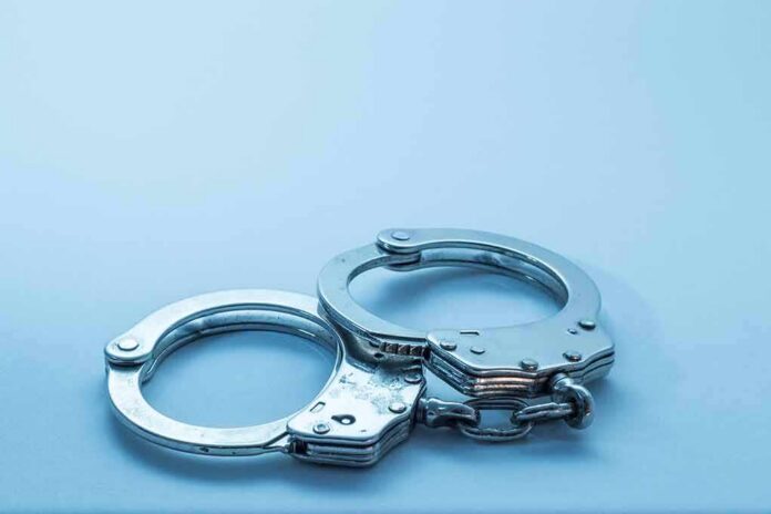 Metal handcuffs on a light blue surface