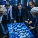 Team of professionals analyzing digital map on interactive table