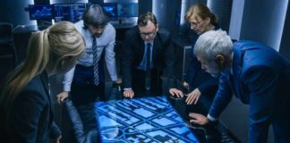 Team of professionals analyzing digital map on interactive table