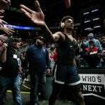 Basketball player in headphones high-fives fans while walking past crowd