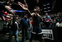 Basketball player in headphones high-fives fans while walking past crowd
