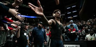 Basketball player in headphones high-fives fans while walking past crowd