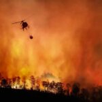 Helicopter fights massive wildfire over burning forest