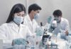 Scientists in lab coats working with test tubes and microscopes