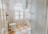 Small tiled bathroom with toilet, sink, and shower