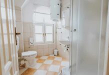 Small tiled bathroom with toilet, sink, and shower